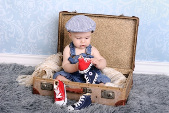 Baby in einem Koffer mit vielen Schuhen