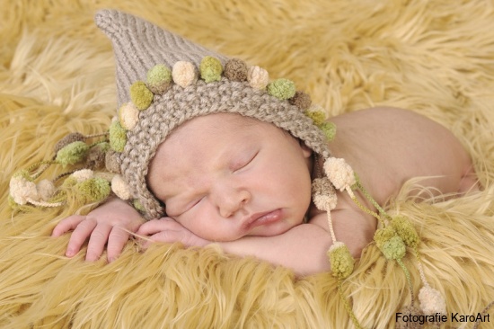 Neugeborenes Baby mit einer Mütze in einem Fell
